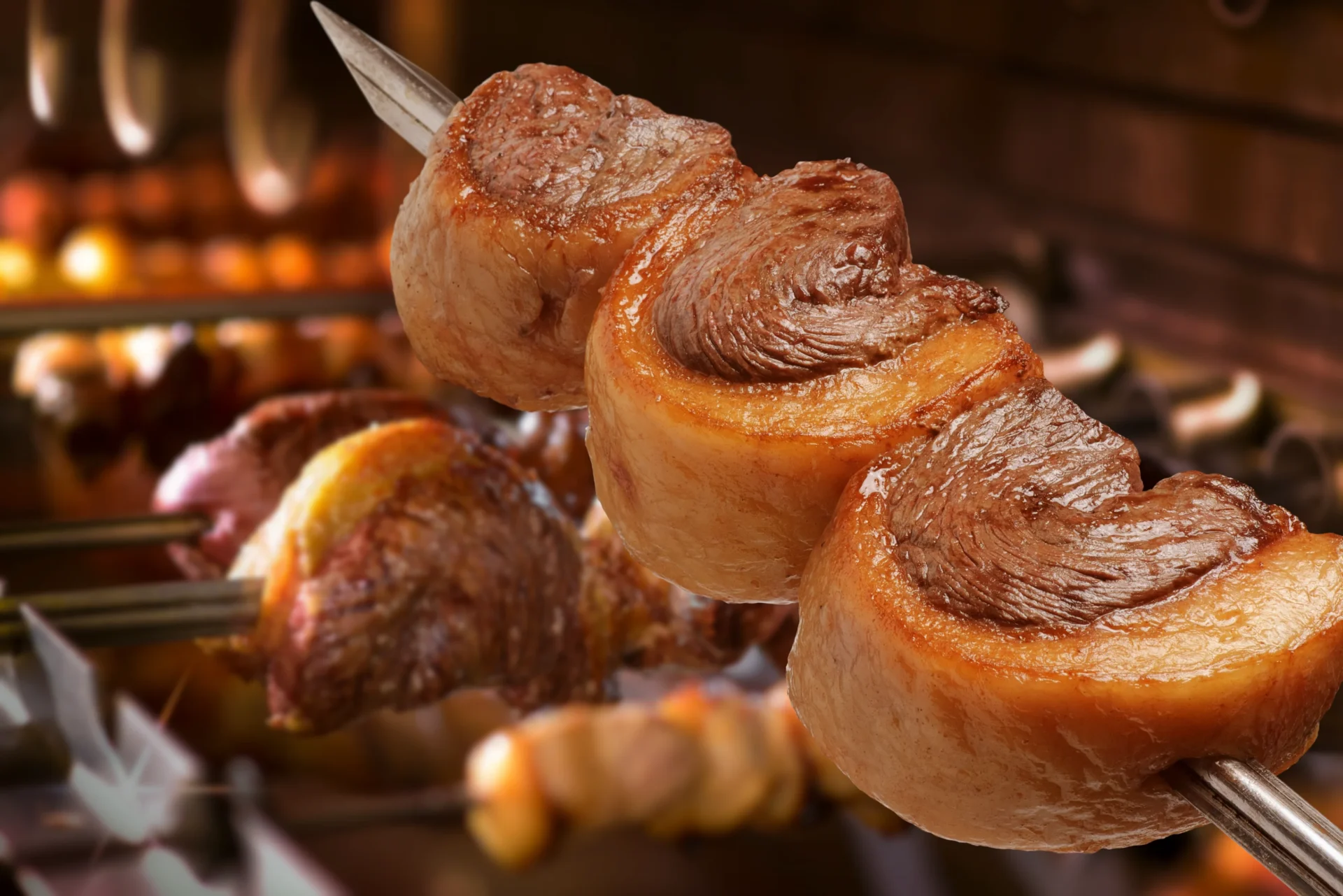 Close-up of meat skewers roasting over a grill.
